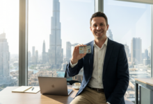 A natural, candid photo of a successful international professional holding a UAE residency card in a modern glass office in Downtown Dubai, with the Burj Khalifa and skyline in the background.